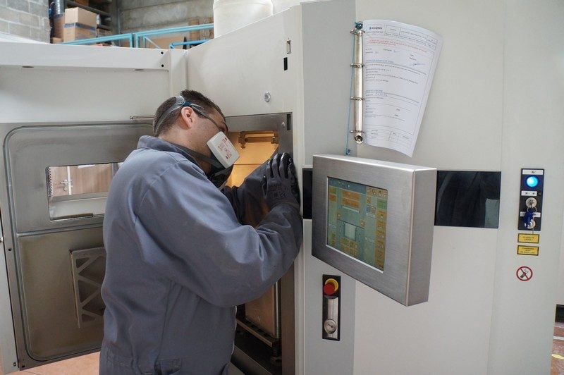 Un technicien nettoie une imprimante après la fabrication d'un objet.