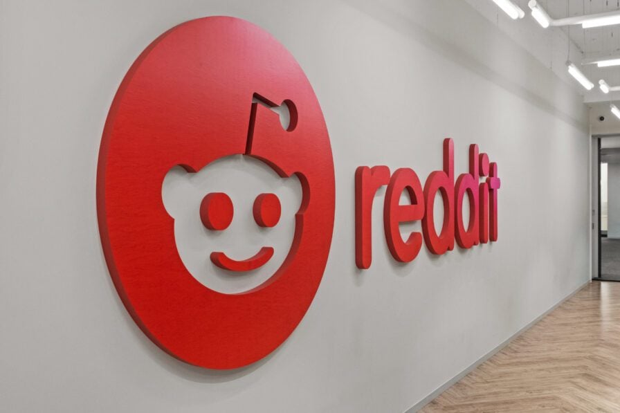Reddit’s red logo mounted on an office corridor wall