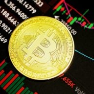 Une pièce de bitcoin posée sur un graphique de cours