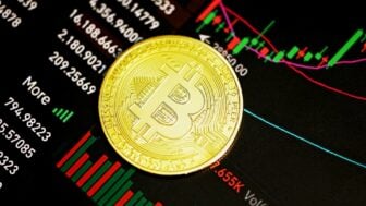 Une pièce de bitcoin posée sur un graphique de cours